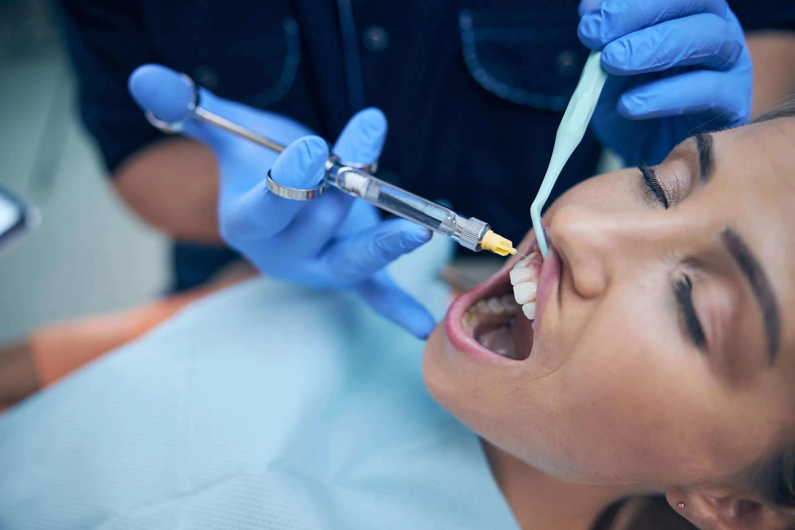 dentist doing injection in woman gum in office